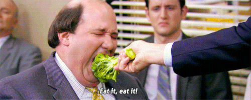 Man shoving broccoli in another man's face