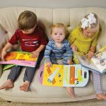 3 children sitting on couch reading books