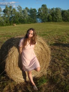 Woman leaning against hay bail in field 