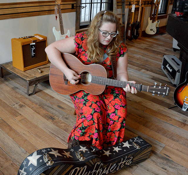 Woman in red floral dress playing guitar